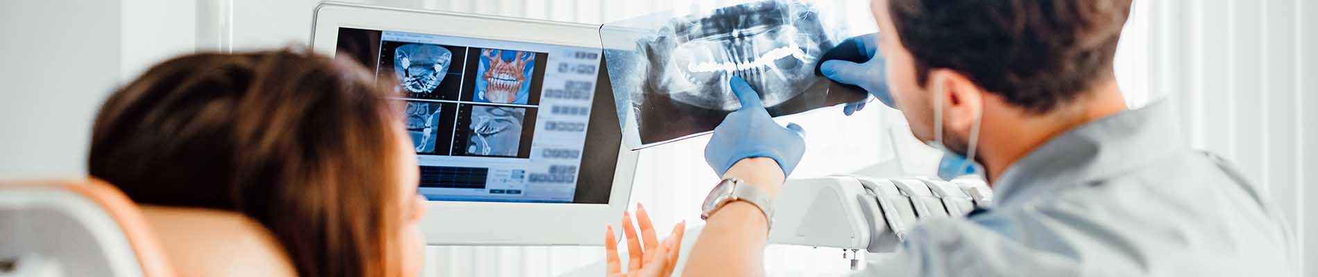 A man and woman are observing a medical monitor displaying a 3D model of a human body, with the man pointing at something on the screen.