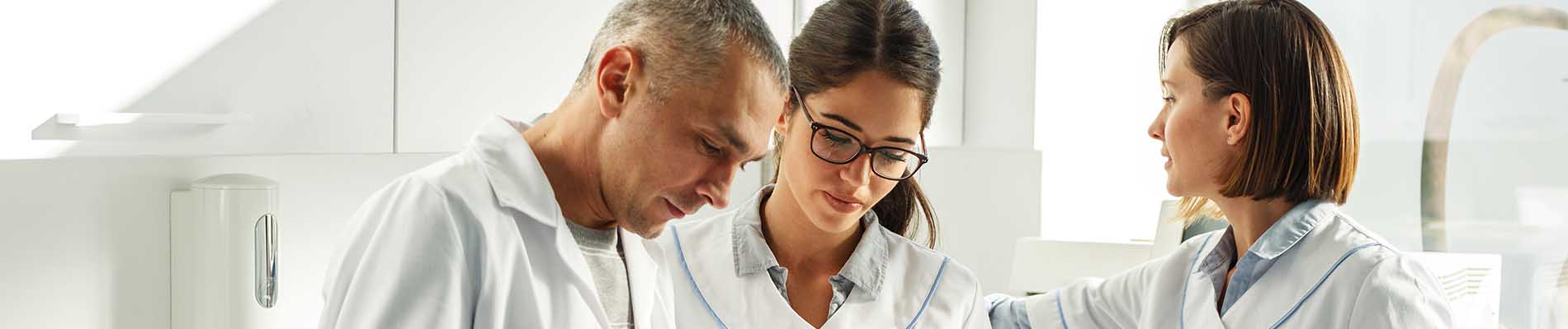 The image features a group of people, presumably professionals given their attire, standing together in an indoor setting that appears to be a laboratory or office environment.