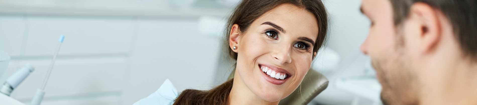 The image shows a modern dental clinic interior with various pieces of equipment, including a dental chair and an X-ray machine.